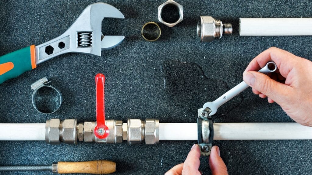 Plumber repairing a pipe valve with an adjustable wrench in Upper Darby
