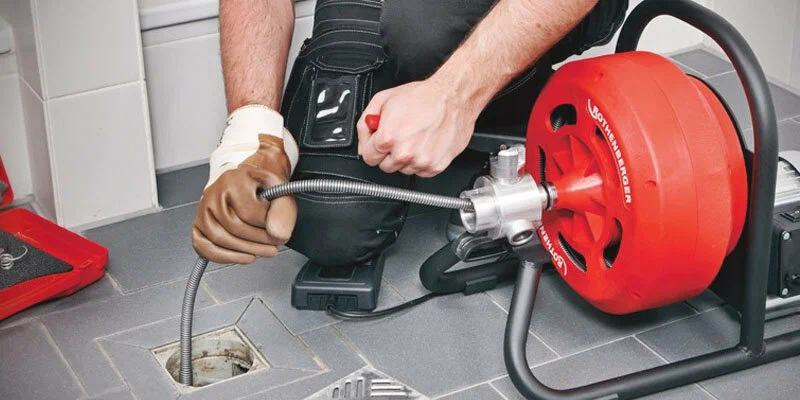 Plumber using a drain-cleaning machine in Upper Darby