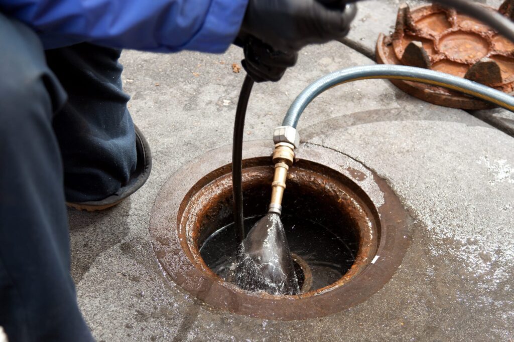 Plumber hydro jetting a sewer line through a manhole in Upper Darby