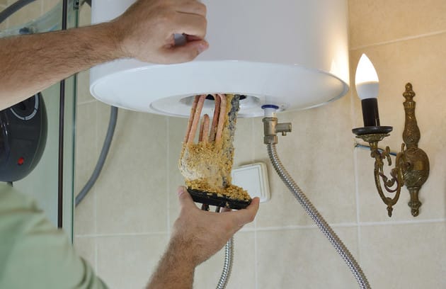Technician removing mineral buildup from a water heater in Upper Darby