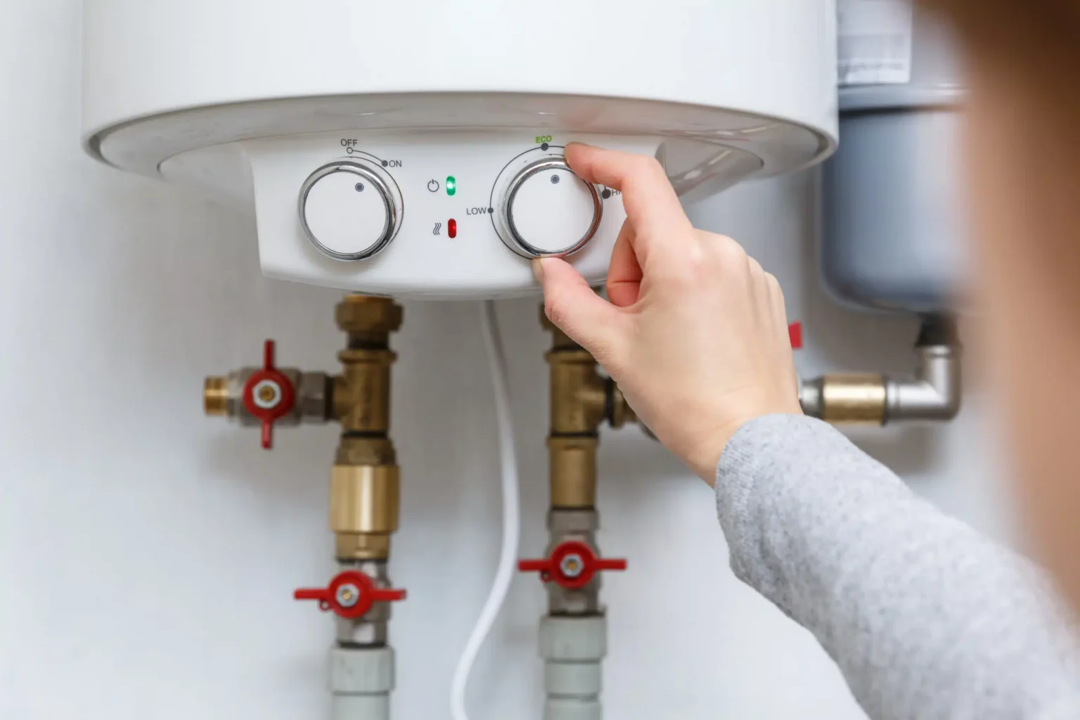 Homeowner adjusting the temperature controls on a water heater in Upper Darby